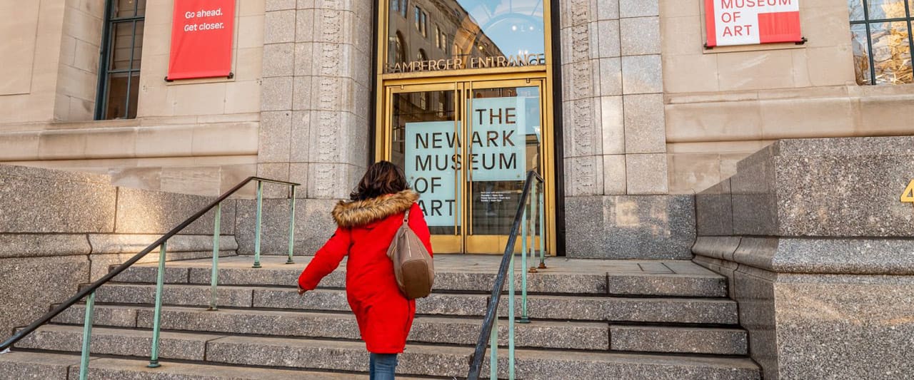 person in red winter coat ascending museum entrance steps