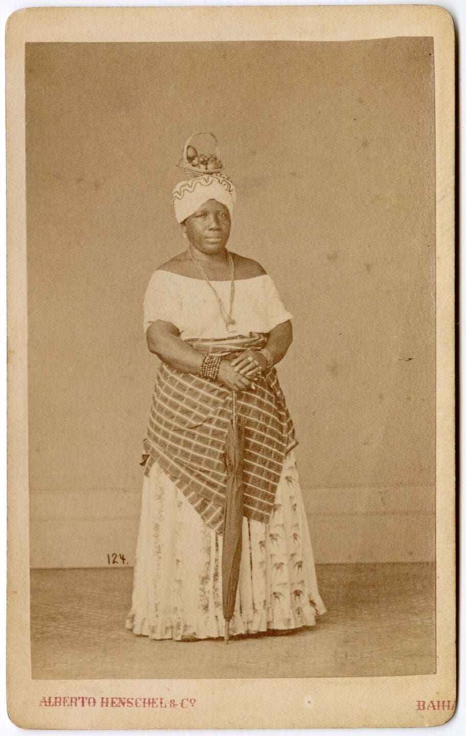 Alberto Henschel, Portrait of a black Brazilian woman standing with a basket of fruit on her head