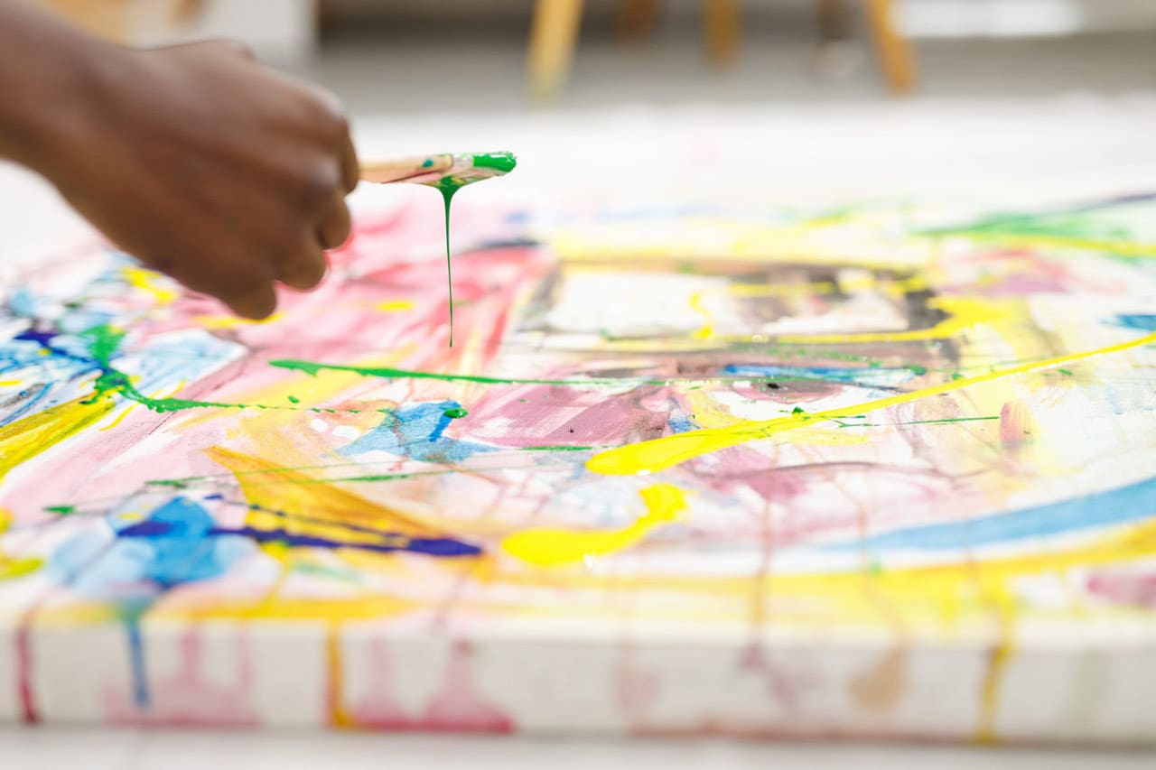 Close up of african american male painter at work painting on canvas in art studio. creation and inspiration at an artists painting studio.
