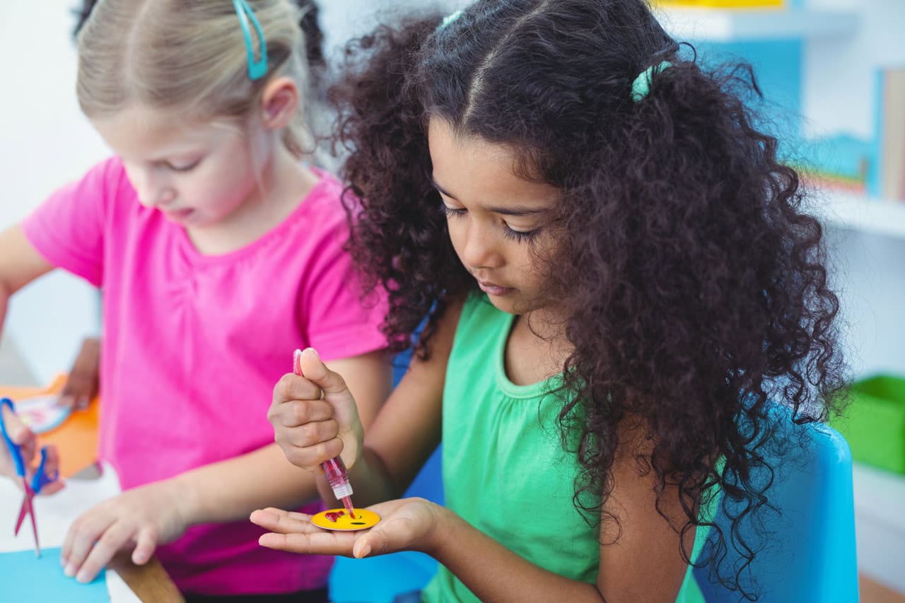 Girls making arts and crafts together at their desk