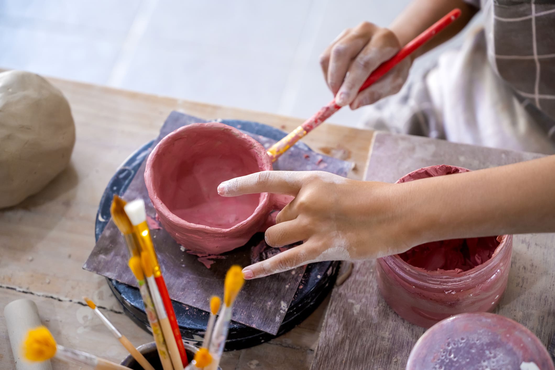 Closeup view of kids making a craft of a porcelain mug from wet clay. Pottery craft clay concept